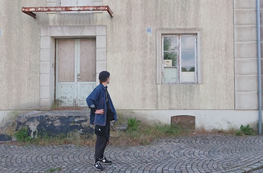 man dressed in helgrose clothes standing looking at window